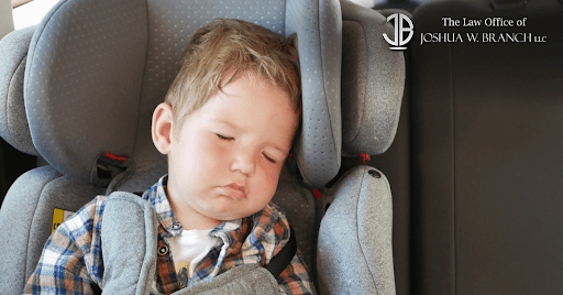 Toddler sleeping in his car seat in the back of a car